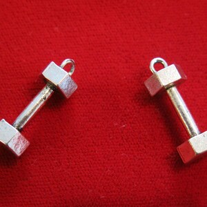 May include: Two silver dumbbell charms with a loop at the top for attaching to a necklace or bracelet.