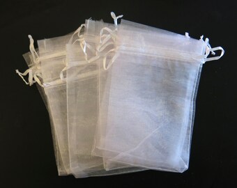 May include: A stack of white sheer organza gift bags with white drawstrings. The bags are made of a delicate, translucent fabric and are perfect for packaging small gifts or favors.