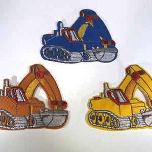 May include: Three embroidered iron-on patches of construction vehicles. The patches are yellow, orange, and blue. Each patch features a digger with a scoop and tracks.
