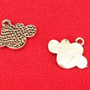 May include: Two silver metal charms shaped like a cloud with a textured surface.