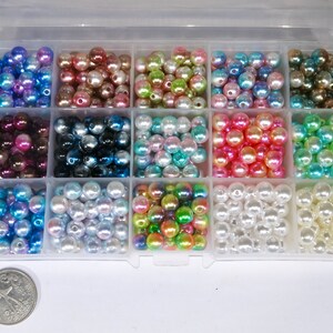 May include: A clear plastic storage box filled with 12 compartments of iridescent pearl beads in various colors, including blue, green, pink, white, and brown.