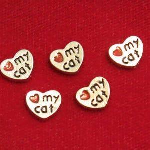 May include: Five silver heart-shaped charms with red hearts and the text "I love my cat" on each charm.