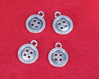 May include: Four silver-toned metal button charms with four holes each. The charms are on a red background.