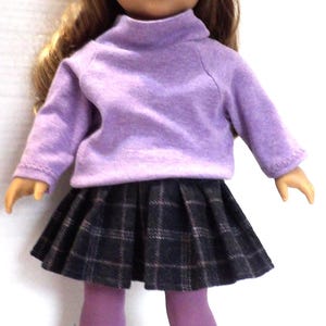 May include: A doll wearing a lavender turtleneck sweater, a plaid pleated skirt, and gray boots. The doll has long brown hair and is wearing purple tights. The boots have brown button details.