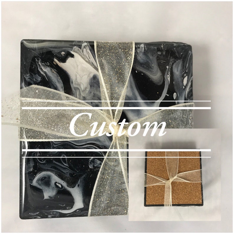 May include: Set of four black and white marble coasters with a silver glitter ribbon tied around them. The coasters are made of resin and have a smooth, glossy finish. The word "Custom" is written on the ribbon.