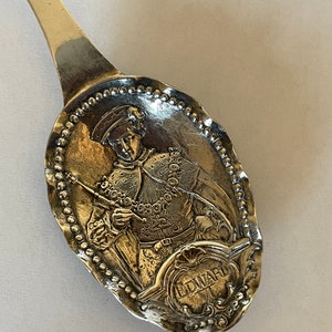 May include: A silver spoon with an ornate design featuring a portrait of a man in a feathered hat and the inscription "EDWARD VI".