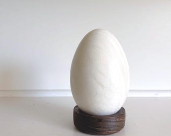 Huevo de mármol grande sobre soporte de madera