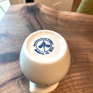 Puede incluir: Jarra de cer&aacute;mica blanca con un logotipo azul y verde que dice "Emerson Creek Pottery Bedford, Va. 2010".