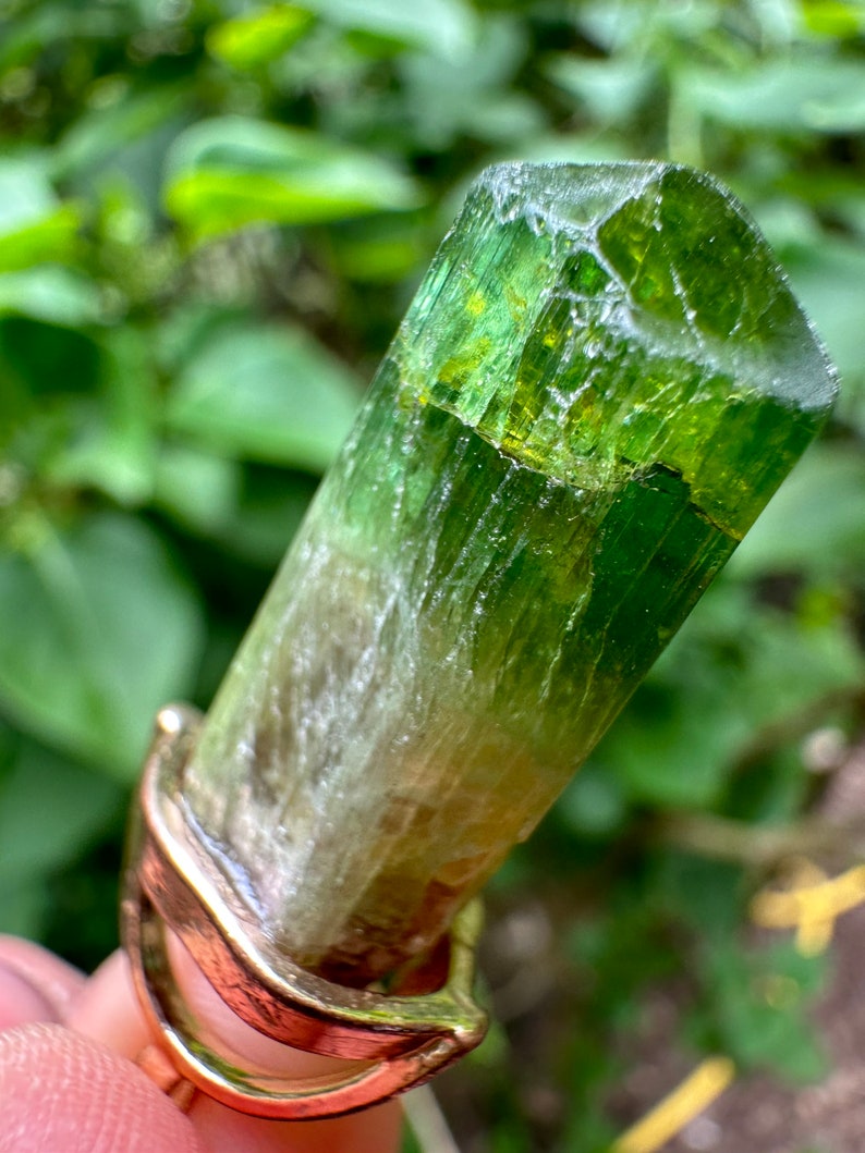 May include: A green and white crystal point set in a gold ring. The crystal is translucent and has a striated texture.