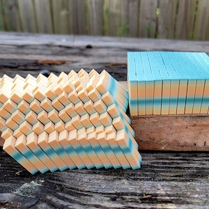 May include: A stack of small, rectangular blocks with a gradient of blue, yellow, and orange colors. The blocks are arranged in a pyramid shape on a wooden surface.
