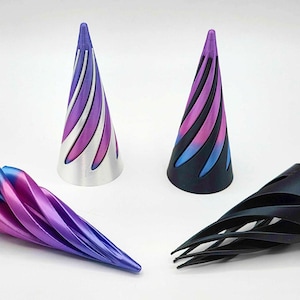 以下が含まれることがあります： 青、紫、黒の色合いの、4つの抽象的な円錐形の彫刻。2つは直立しており、1つは銀と紫、もう1つは黒と紫です。他の2つは横たわっており、1つは青と紫、もう1つは黒です。