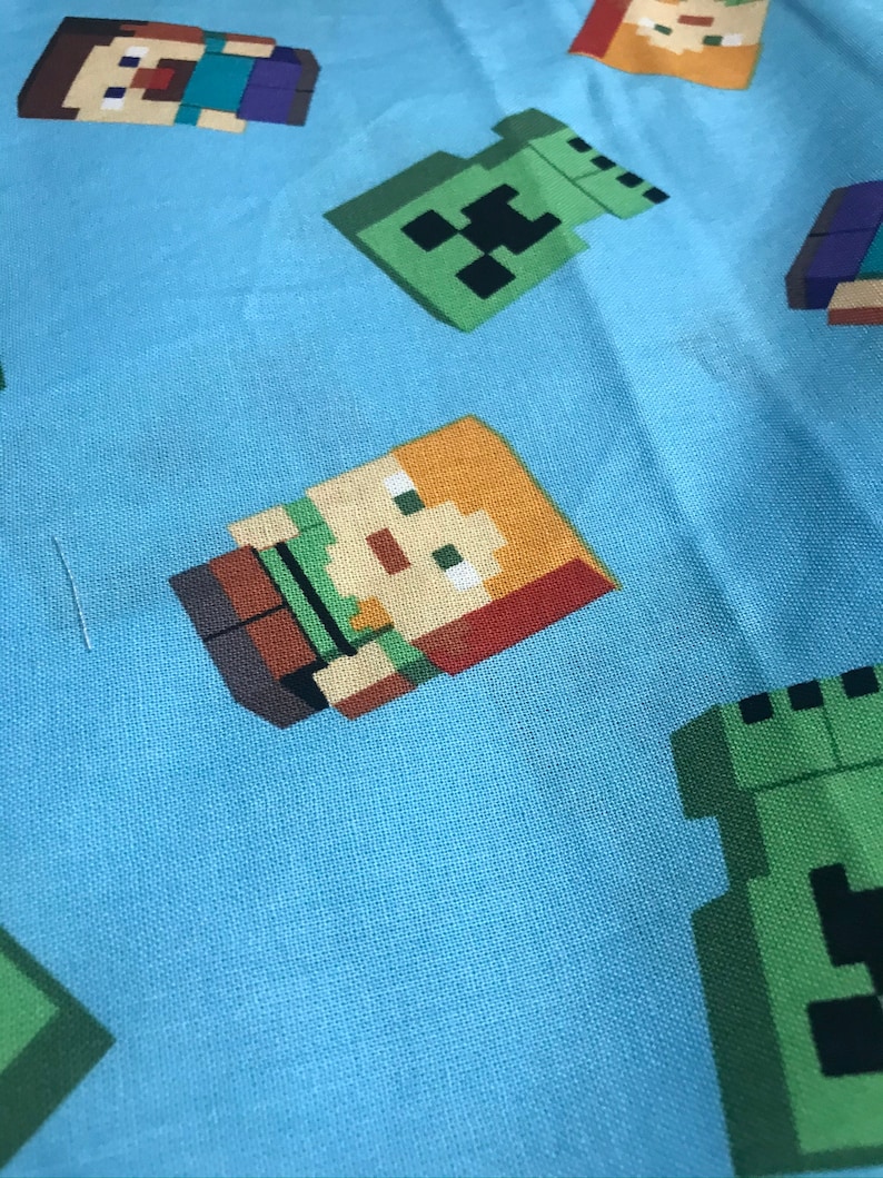 Puede incluir: Tela azul con un patr&oacute;n repetido de personajes de Minecraft. Los personajes incluyen a Steve, Alex y un Creeper.
