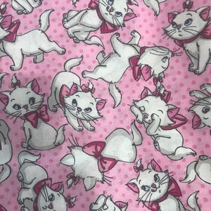 Puede incluir: Tela rosa con un patr&oacute;n repetido de gatos blancos con lazos rosas. Los gatos est&aacute;n en varias poses, algunos est&aacute;n sentados, otros de pie y otros mirando hacia un lado.
