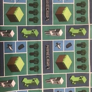 Puede incluir: Una tela azul y verde con un patr&oacute;n repetido de personajes y bloques de Minecraft. La tela presenta el logotipo de Minecraft, un creeper, un esqueleto, una espada, un bloque de tierra y &aacute;rboles.