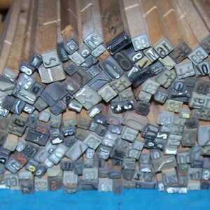 May include: A large collection of wooden blocks with metal numbers and letters. The blocks are arranged in a random pattern and are stacked on top of each other.