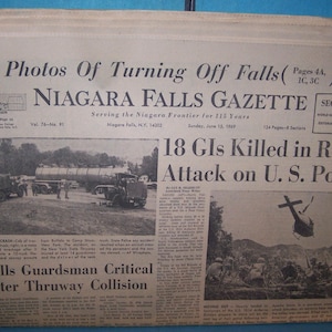 May include: A black and white newspaper clipping with the headline "18 GIs Killed in Red Attack on U.S. Post". The newspaper is titled "Niagara Falls Gazette" and the date is June 16, 1969.