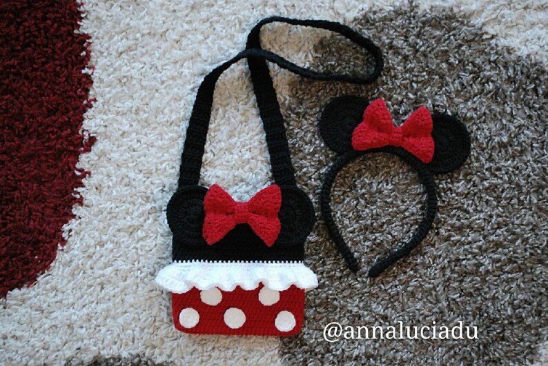 Pu&ograve; includere: Un set di borsa e fascia per capelli Minnie Mouse in crochet nero e rosso. La borsa ha un bordo a balze bianche e pois rossi. La fascia ha orecchie nere con fiocchi rossi.