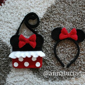 Pu&ograve; includere: Una borsa Minnie Mouse in crochet nero e rosso con un volant bianco e pois rossi. &Egrave; incluso anche un cerchietto abbinato in crochet nero e rosso con orecchie di Minnie Mouse. Il testo '@annaluciadu' &egrave; visibile nell'immagine.