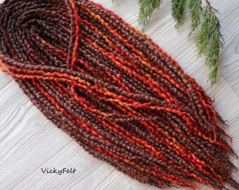 May include: A long strand of brown, orange, and red wool yarn with a slight ombre effect. The yarn is twisted and textured, creating a unique look. The yarn is perfect for crafting projects like crocheting or knitting.