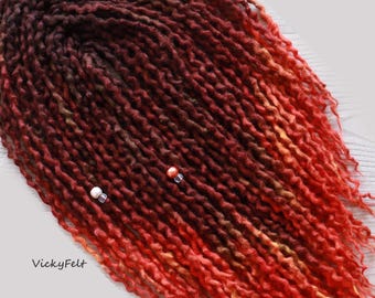 May include: Red, orange, and brown wool dreadlocks with beads. The dreadlocks are ombre, transitioning from dark brown to red and orange.