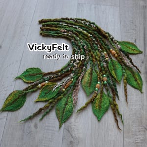 May include: A set of green and brown felted hair extensions featuring multiple strands with textured twists, integrated felt leaves in various shades of green, and decorative wooden and green beads. The text VickyFelt ready to ship is visible.