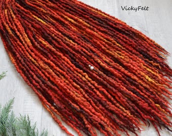 May include: A set of long, red, orange, and brown wool dreadlocks. The dreadlocks are made of wool yarn and are approximately 24 inches long.