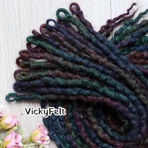 May include: A collection of dark-toned felted wool dreadlocks in shades of deep purple, forest green, and navy blue. Each individual strand features a small loop at the top end. The text VickyFelt is printed in white on the lower left side.