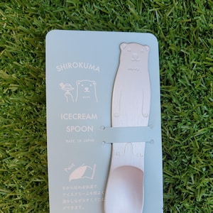 Peut inclure: Une carte bleu clair avec une illustration de ours polaire blanc et le texte "SHIROKUMA ICECREAM SPOON MADE IN JAPAN". La carte présente une cuillère à glace en forme d'ours polaire argentée.