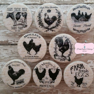 May include: Set of 8 round wooden signs with black and white illustrations of farm animals and text. The signs feature chickens, roosters, a cow, and eggs. The text includes "Farm Fresh Milk", "Dairy Farm", "Moulins de Provence", "Le Cour de Ferme", "Organic Chicken Feed", "Farm Fresh Eggs", "Ocufs Frais Quotidions", and "Le Poulet".