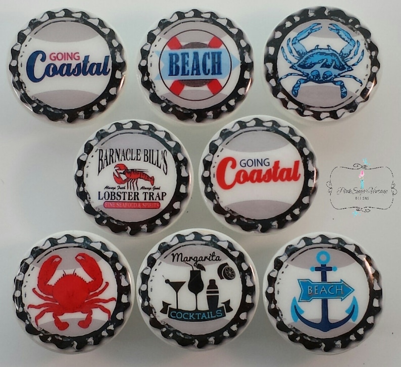 Peut inclure: Une collection d'aimants en forme de bouchons de bouteilles avec des motifs c&ocirc;tiers et de plage. Les aimants pr&eacute;sentent des images de crabes, d'ancres et des textes tels que "Going Coastal", "Beach" et "Margarita Cocktails". La palette de couleurs comprend le bleu, le rouge et le blanc.