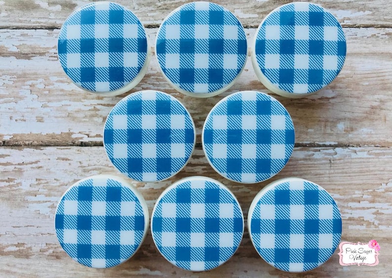 Pu&ograve; includere: Otto pomelli rotondi in ceramica bianca con un motivo a quadri blu e bianchi.