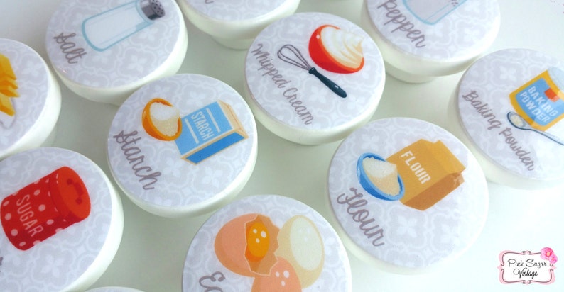 May include: Set of 10 white ceramic knobs with colorful illustrations of baking ingredients, including salt, sugar, flour, starch, whipped cream, baking powder, eggs, and pepper. Each knob features a different ingredient and the name of the ingredient is written below the illustration.
