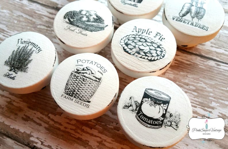 Peut inclure: Ensemble de 8 boutons ronds en c&eacute;ramique blanche avec des illustrations en noir et blanc de divers aliments. Les boutons portent les inscriptions "Rosemary", "Fresh Fruits", "Apple Pie", "Vegetables", "Potatoes", "Farm Seeds", et "Tomatoes".