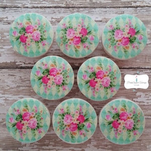 以下が含まれることがあります： 花柄の丸い木製ノブが8個。ノブは薄い緑色の背景に白いひし形模様が施されています。花はピンク、白、黄色です。