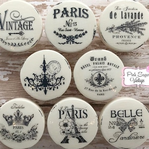 Peut inclure: Neuf carreaux de céramique ronds blancs avec des lettres et des motifs noirs. Les carreaux présentent des thèmes parisiens, notamment des motifs vintage, hôteliers et floraux. Les carreaux sont décorés de textes tels que "Vintage", "Paris", "Le Jardin de Lavande", "Grand Hotel Palais Royale", "Belle Jardiniere", "J'aime Paris", et "Tralelin Paris".