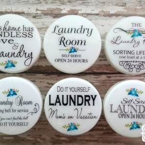 May include: Six white round laundry room signs with different sayings. The signs have blue and pink flowers and green leaves. The sayings include: "This home has endless love & laundry", "Laundry Room Self Serve Open 24 Hours", "The Laundry Room Sorting Life Out One Load At A Time", "Laundry Room Ring Bell For Service If You Can't Find The Bell Do It Yourself", "Do It Yourself Laundry Mom's On Vacation", "Self Serve Laundry Open 24 Hours".