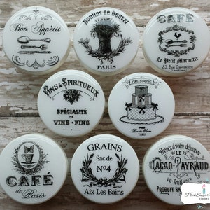 May include: Set of 8 white ceramic jar lids with black and white vintage French-inspired designs. The lids feature text such as "Bon Appetit", "Cafe de Paris", "Vins & Spiritueux", "Grains", and "Cacao Payraud".