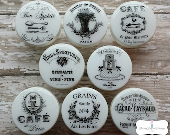 May include: Set of 8 white ceramic jar lids with black and white vintage French-inspired designs. The lids feature text such as "Bon Appetit", "Cafe de Paris", "Vins & Spiritueux", "Grains", and "Cacao Payraud".