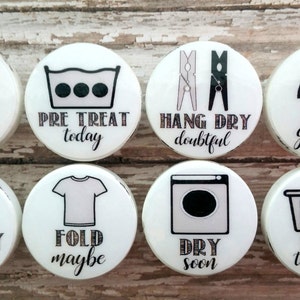 Peut inclure: Huit aimants ronds blancs pour le linge avec des icônes et du texte noir et blanc. Les aimants présentent des phrases liées au linge telles que "Wash later", "Pre Treat today", "Hang Dry doubtful", "Iron get real", "Laundry always", "Fold maybe", "Dry soon", et "Sort tomorrow".
