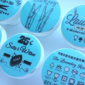 Puede incluir: Conjunto de seis pomos de cerámica azul turquesa con varios diseños de temática de lavandería. Los diseños incluyen pinzas para la ropa, símbolos de lavado y texto como "Laundry", "Our home has endless love and laundry", "25¢ Soap & Water", y "The Laundry Room".