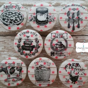 Peut inclure: Neuf boutons ronds en bois avec un fond blanc et des étoiles rouges. Chaque bouton présente une illustration en noir et blanc sur le thème de la ferme. Les illustrations comprennent une tarte aux pommes, des tomates, des cuillères, des biscuits et de la sauce, la vie à la ferme, du lait frais de la ferme, des pommes de terre et des œufs frais de la ferme.