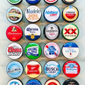 Peut inclure: Une collection de 18 bouchons de bouteille ronds représentant divers logos de bière, dont Budweiser, Miller Lite, Coors Light, Corona Extra et Guinness. Les bouchons sont noirs avec un bord blanc et sont disposés en grille sur une surface blanche.