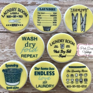 May include: A set of ten yellow and white round laundry themed cookie decorations. The decorations feature various laundry-related phrases and symbols, such as "Wash Dry Fold Repeat", "Laundry Room", and "Our home has endless love and laundry".