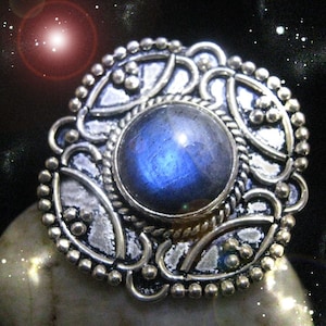 May include: A silver ring with an intricate design featuring a large blue gemstone in the centre.