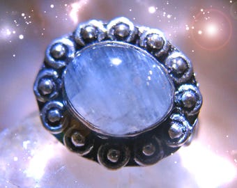 May include: A silver ring with a large, oval-shaped, light blue gemstone set in a decorative, ornate silver setting.