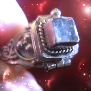 Puede incluir: Un anillo de plata con una piedra preciosa clara y facetada engastada en un engaste de bisel. El anillo tiene detalles intrincados y un diseño de cuerda alrededor de la piedra.