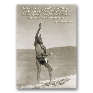 May include: A black and white photo of a Native American man standing with his arm raised in the air. The man is wearing traditional clothing and a headdress. The photo is set against a backdrop of a desert landscape. The text "Looking behind, I am filled with gratitude, looking forward, I am filled with vision, looking upwards, I am filled with strength, looking within, I discover peace. Quero Apache Prayer" is printed below the image.