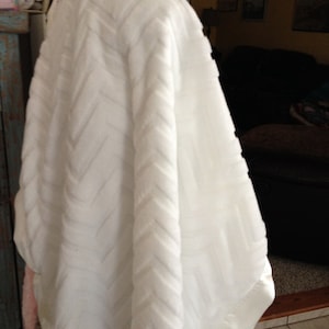 May include: White plush blanket with a chevron pattern. The blanket is folded and draped over a surface.