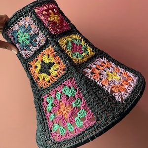 May include: A black crocheted lampshade with colourful squares in shades of pink, green, orange, and yellow.