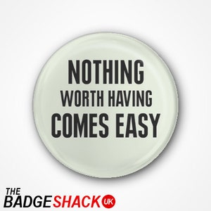 May include: A round, off-white button with the text "NOTHING WORTH HAVING COMES EASY" in bold, black letters. The button has a glossy finish and a slight shadow effect. The Badge Shack UK logo is at the bottom.